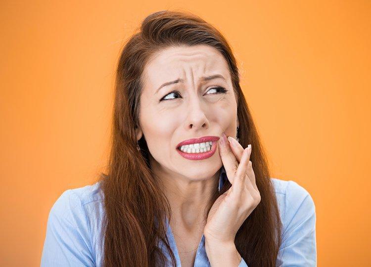 Woman holding jaw from tooth pain during an emergency 
